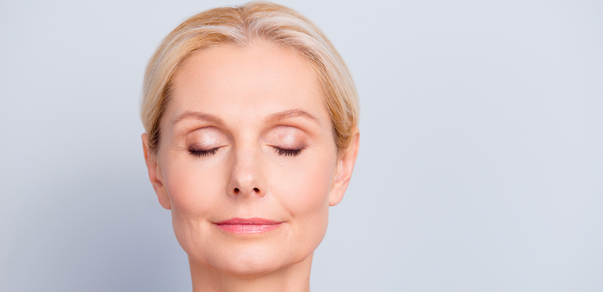 Middle-aged woman leaned on sofa resting in living room cools herself with orange colour hand fan touch forehead feels unwell suffers from unbearable hot summer weather at home without airconditioner